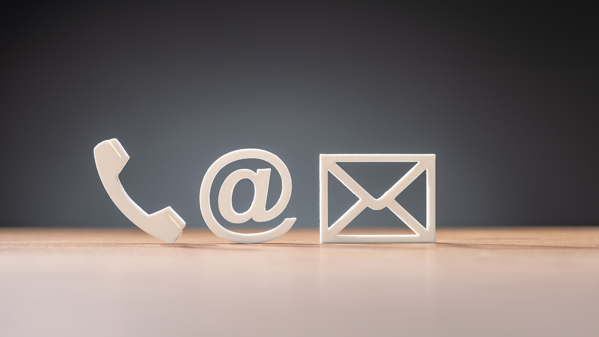 An image of a white enamel phone with an email symbol, placed against a dark background.