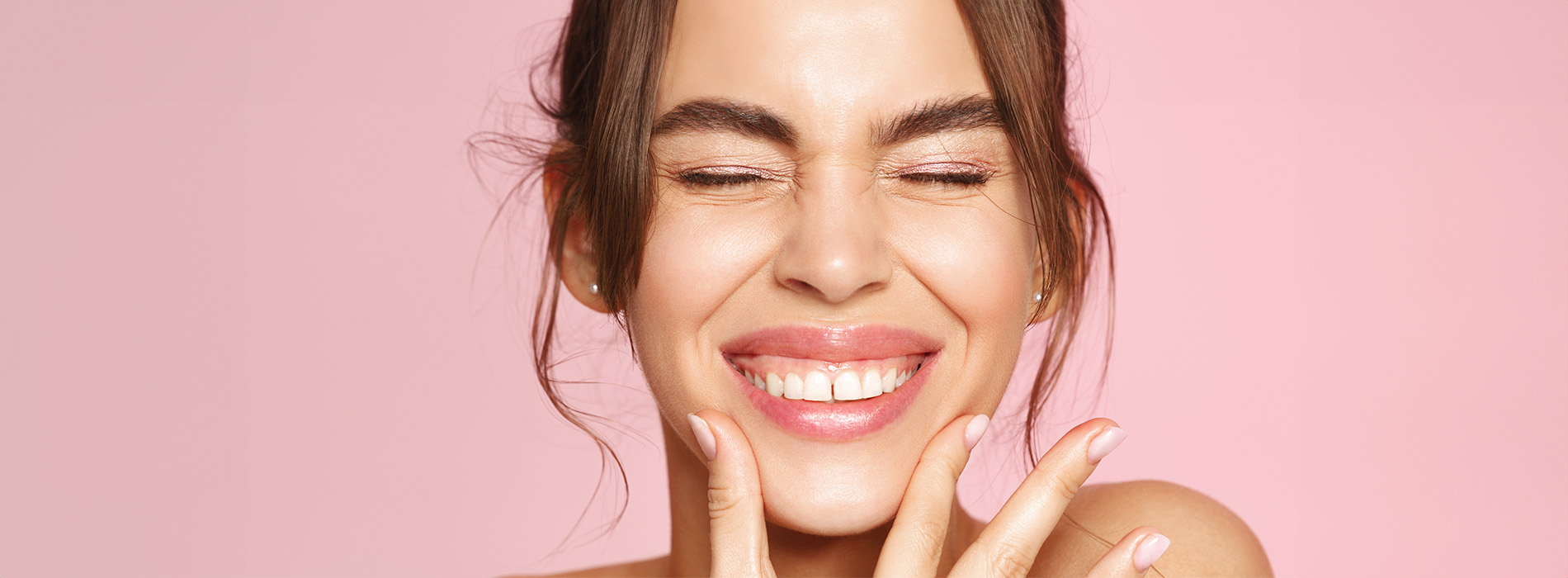 The image is a photograph of a woman with her mouth open, displaying a wide smile. She appears to be in her mid-twenties and has short hair. Her expression conveys a sense of joy or surprise.