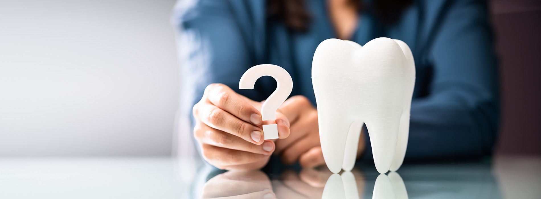 The image shows a person holding a tooth model, possibly in a dental or medical setting.