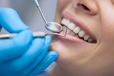 Woman in a dental chair receiving dental care with a smiling expression.