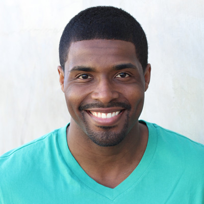 An elderly couple is smiling and embracing each other, posing for a photograph with a scenic backdrop.