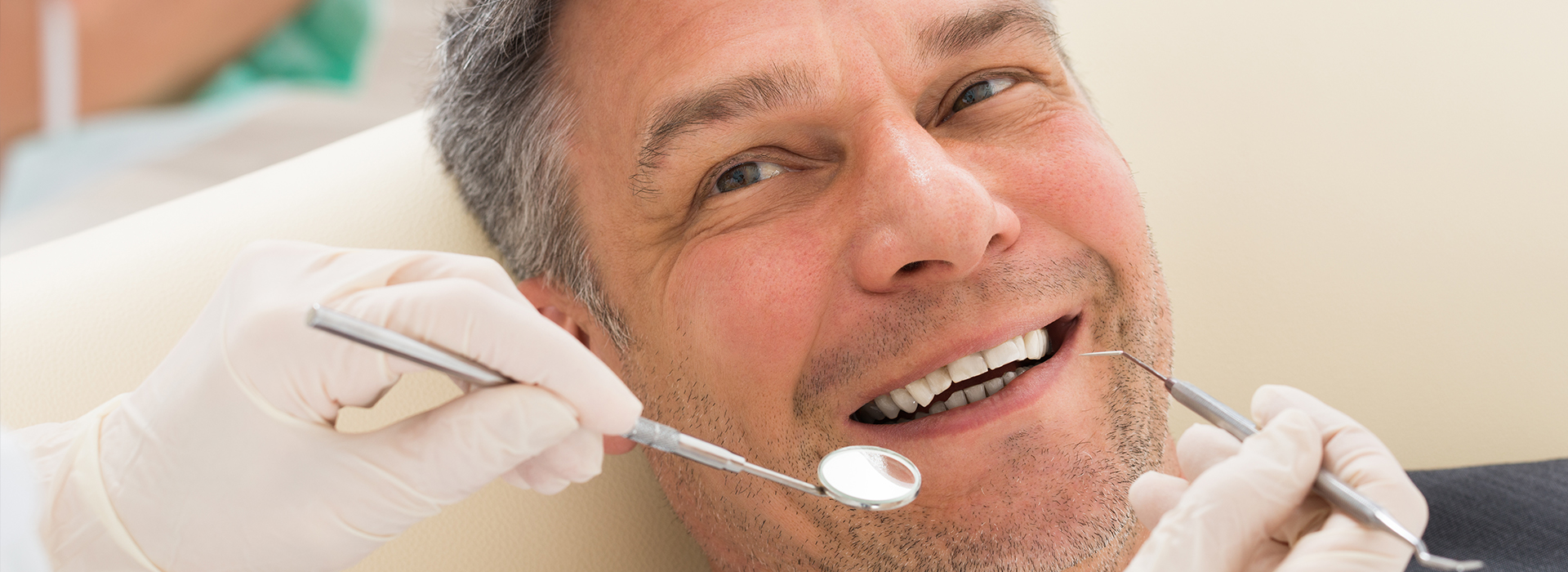 Man in a dental chair receiving dental treatment, smiling and looking at the camera.