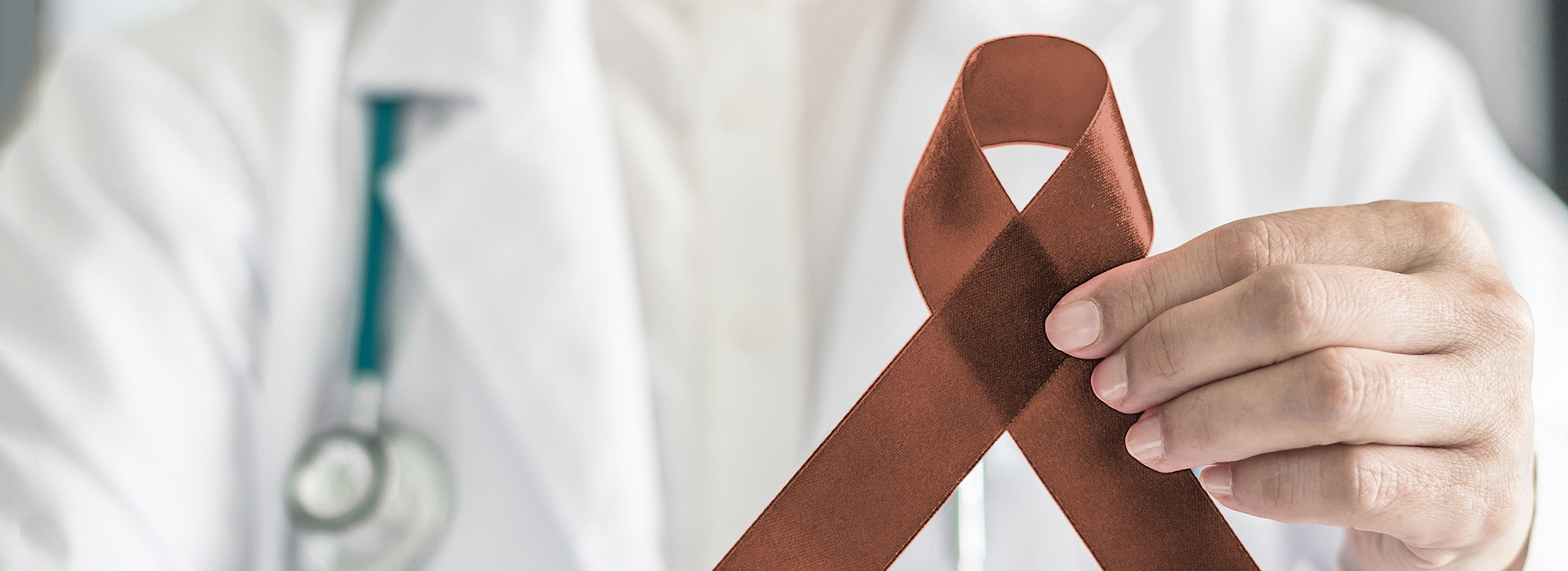 The image shows a person holding a tie with a ribbon symbol, likely representing awareness for a specific cause or condition.