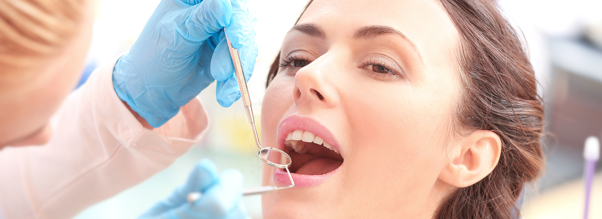 A woman receiving dental care, with a dentist working on her teeth while she is seated in a dental chair.