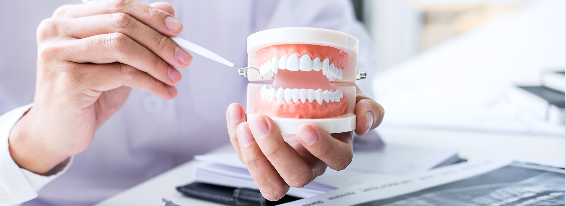 A person holding a toothbrush with a toothpaste tube, examining the bristles against their teeth.