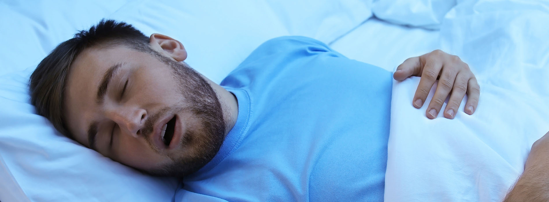 A man sleeping in bed with a pillow over his face.