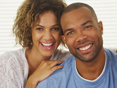 A man and a woman smiling at the camera, with the man wearing a blue t-shirt.
