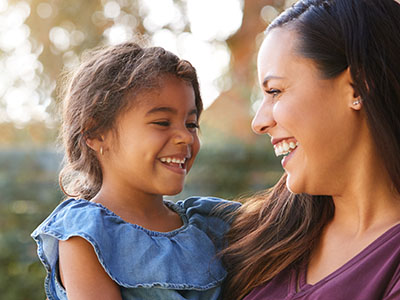 The image depicts a woman and a young child smiling at the camera, with the woman holding the child.