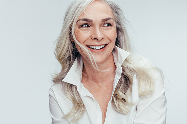 A woman with short hair, smiling broadly at the camera against a neutral background.