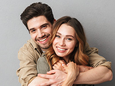 The image features a man and woman embracing each other in a warm pose, smiling at the camera.