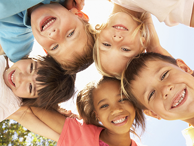 A group of children, with diverse expressions and hair colors, gathered in a circle for a photo.